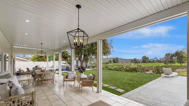 A covered patio with a dining area, seating, and a view of a landscaped garden. - Stunning Home with Hot Tub, Golf Course Views & Close to all So Cal Attractions! (Mission Viejo)