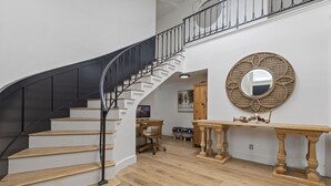 A staircase with black railings leading to an upper floor, a wooden console table, and a round mirror on the wall. - Stunning Home with Hot Tub, Golf Course Views & Close to all So Cal Attractions! (Mission Viejo)