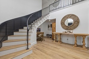 Staircase leads to an upper level, featuring a console table and decorative mirror.