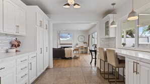A spacious kitchen with white cabinetry, a dining area with a view, and a cozy living room. - Stunning Home with Hot Tub, Golf Course Views & Close to all So Cal Attractions! (Mission Viejo)