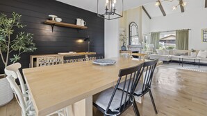 A dining area with a wooden table and chairs, a black wall with shelves, and a hanging light fixture. - Stunning Home with Hot Tub, Golf Course Views & Close to all So Cal Attractions! (Mission Viejo)