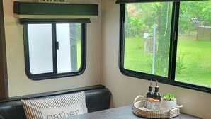 Ein gemütliches Wohnmobil-Interieur mit Essbereich, einer Sitzbank und einem Fenster mit Blick ins Freie.