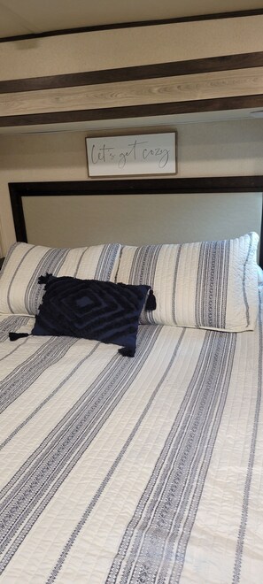 A bed with striped bedding and a dark pillow.