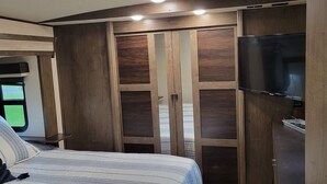 Ein Schlafzimmer mit einem Bett, einem Fernseher und einem Kleiderschrank mit Spiegel.