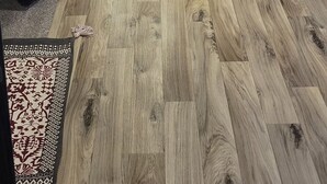 Ein Zimmer mit Holzboden, einem Fernseher und Holzschränken.