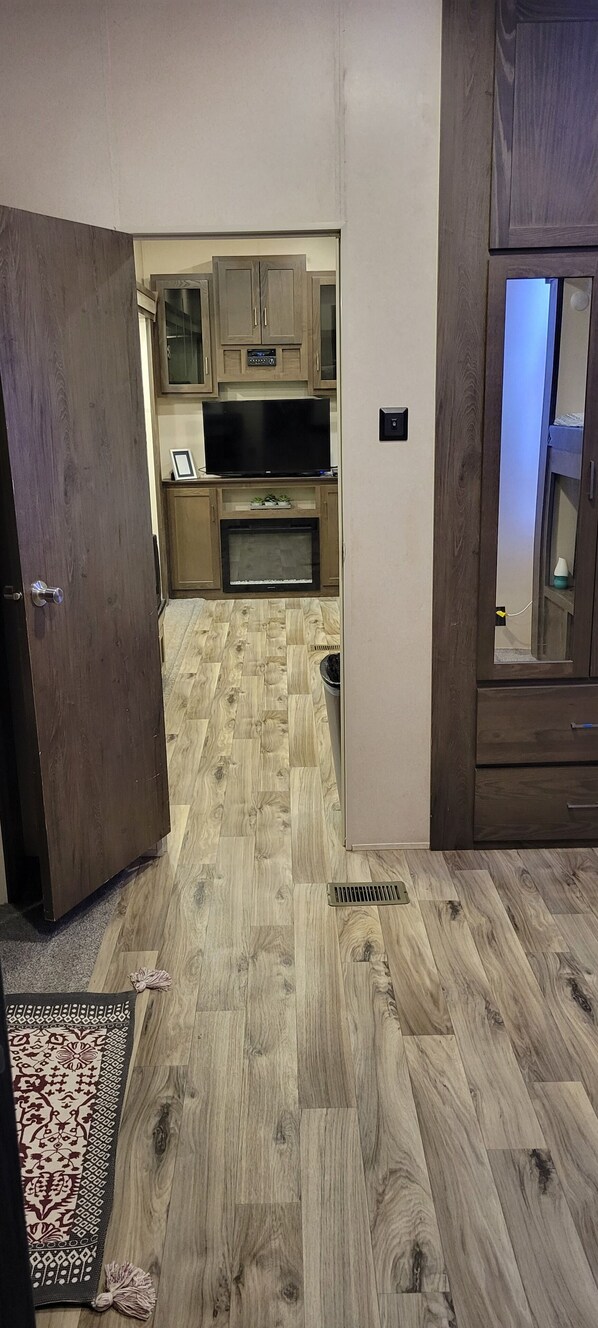 A room with a wooden floor, a television, and wooden cabinets.