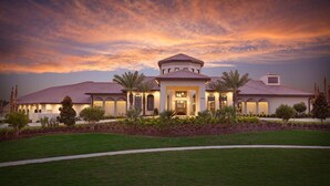 A large, single-story house with a central entrance, surrounded by a well-maintained lawn and palm trees.