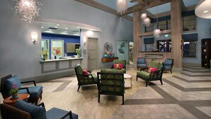 A spacious lobby with a reception desk, multiple seating areas, and decorative lighting.