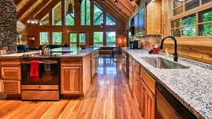 Una cocina amplia con una isla grande, armarios de madera y una pared decorativa de piedra.