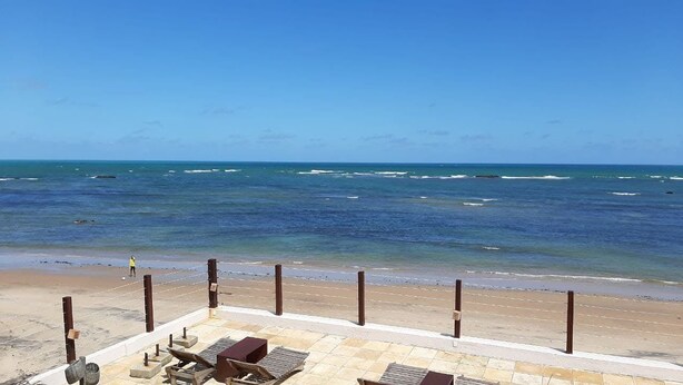 A beach with a clear view of the ocean, a sandy shore, and a few lounge chairs and umbrellas. - Recanto Há Mar (Maceió)