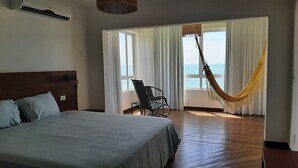 A hotel room with a bed, a chair, a hammock, and a view of the sea. - Recanto Há Mar (Maceió)