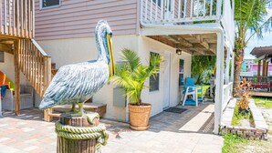 A patio area with a large pelican statue, a potted palm tree, and outdoor furniture.