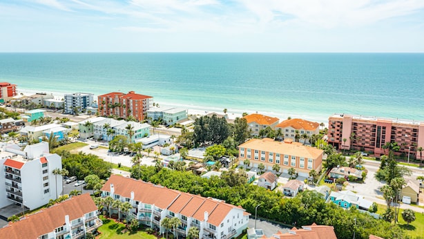 A coastal resort area with beachfront buildings, a clear view of the ocean, and a mix of residential and commercial structures.