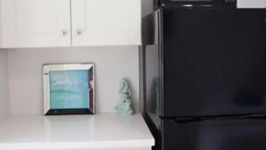 A kitchen with white cabinets, a black refrigerator, and a chalkboard with writing on the countertop.