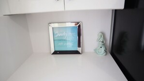A framed sign with text under a cabinet, and a small figurine beside it.