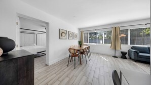 A modern, well-lit room with a dining area, a sofa, and a bed. - Newly Remodeled Home with Spacious Backyard! (Fort Lauderdale)
