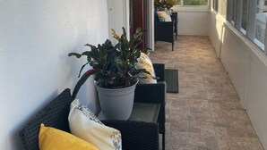 Een overdekt terras met rieten meubels en plantenpotten.