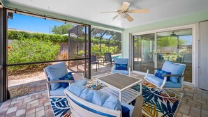 A sunlit patio with a glass enclosure, outdoor seating, and a ceiling fan. - Beautiful Pool Home, 6 Min. to Beaches, Sleeps 8, Great for Families! (Largo)