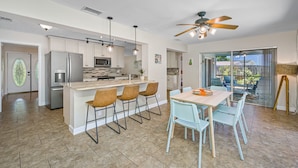A modern kitchen with a central island, bar stools, and a dining table with chairs. - Beautiful Pool Home, 6 Min. to Beaches, Sleeps 8, Great for Families! (Largo)