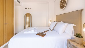 A neatly made bed with white linens, a wooden headboard, and a small potted plant on the nightstand. - Altamar Cielo (Javea / Xàbia)