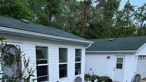 A white house with a covered patio, outdoor seating, and a small garden. - A  peaceful country retreat a block away from the beach,with beautiful sunsets.  (Dunnottar)