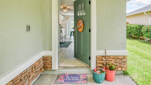 A front entrance with a green door, a doormat, and potted plants. - Wynfield Place (St. Augustine)