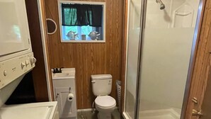 Une petite salle de bain comprenant une douche, des toilettes et un petit lavabo.