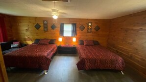 Une chambre avec deux lits, chacun agrémenté de draps à motifs, une petite table avec deux lampes et une fenêtre avec des rideaux.