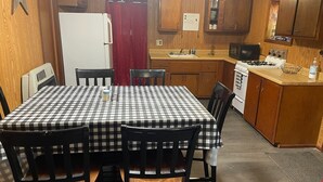 Une cuisine de taille modeste, avec une nappe à carreaux, des placards en bois, un four à micro-ondes, une cuisinière et un réfrigérateur.