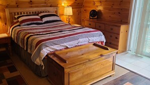 A wooden cabin bedroom with a bed, nightstands, and a wooden dresser. - Cute romantic studio  (Moultonborough)