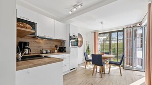 Eine moderne Küche mit weißen Schränken, einer Holz Arbeitsplatte und einem Essbereich mit Tisch und Stühlen.