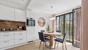 Eine moderne Küche mit weißen Schränken, einer Holz Arbeitsplatte und einem Essbereich mit rundem Tisch und Stühlen.