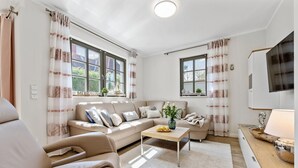 Ein modernes Wohnzimmer mit einer Couch, einem Couchtisch und einem Flachbildfernseher.