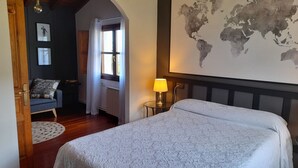 A bedroom with a large bed, a world map on the wall, a lamp, and a view of the outdoors through a window. - Gestiona2R. House on the coast of Llanes for 8 people (Llanes)