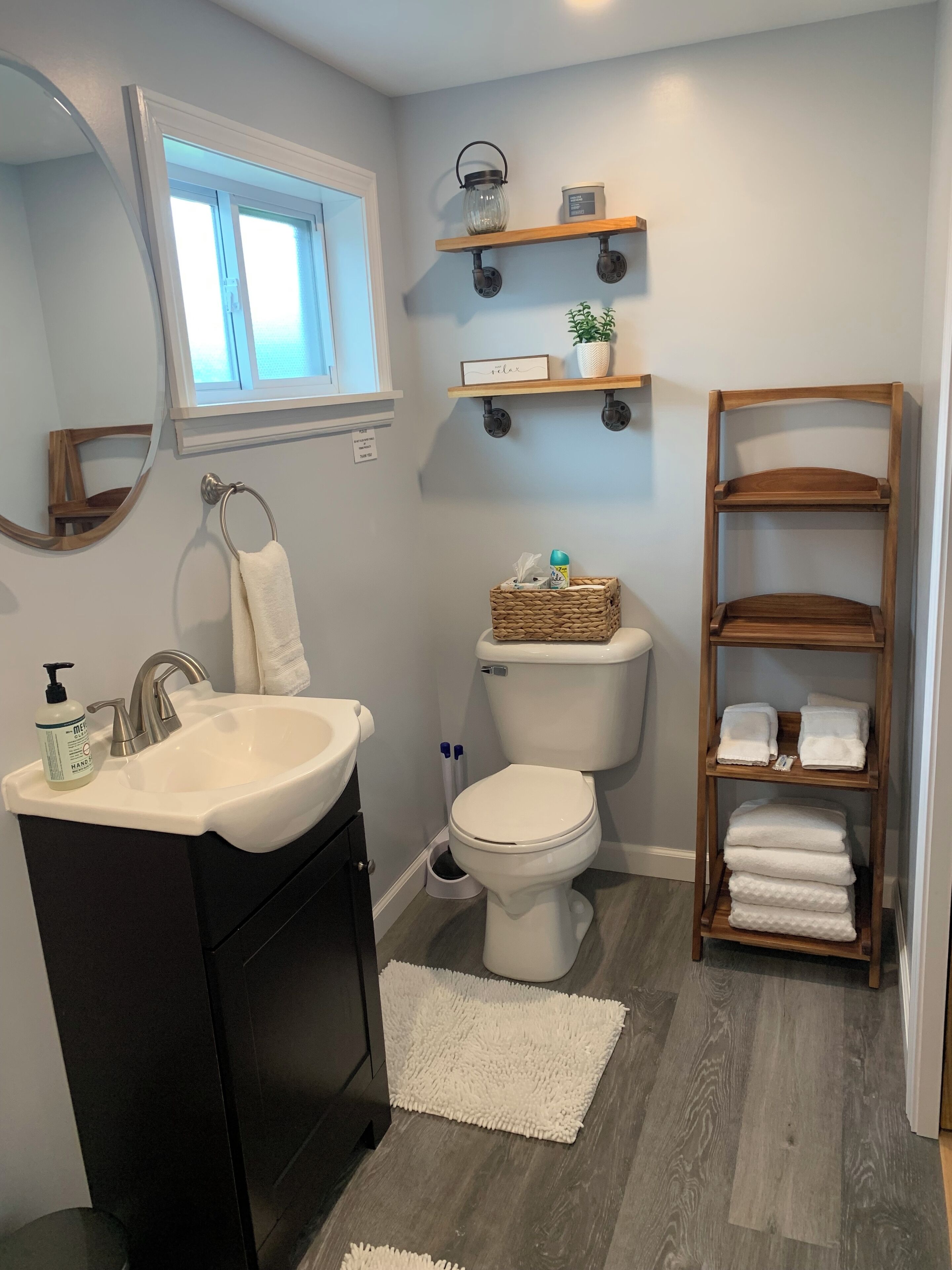 A bathroom with a sink, toilet, and wooden shelves.