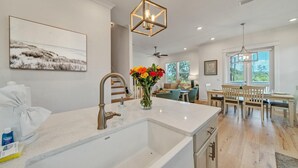 Een moderne keuken met een groot eiland, een eetgedeelte met tafel en stoelen, en een zithoek met een bank en salontafel.
