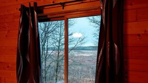 Una camera tipo baita con una grande finestra, pareti in legno e un letto con biancheria bianca.