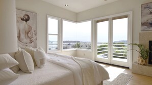 Un dormitorio con una cama grande, varias ventanas y vistas a la ciudad.