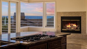 Una cocina con una isla grande, una chimenea y vistas al océano a través de amplios ventanales.