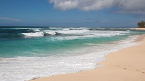 Una playa con olas, agua cristalina y una orilla arenosa.