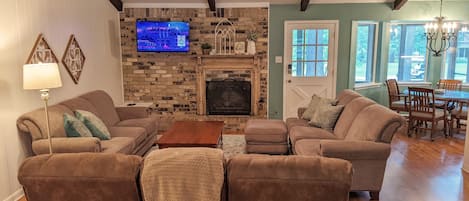 Una sala de estar con chimenea, televisor y comedor con muebles de madera.