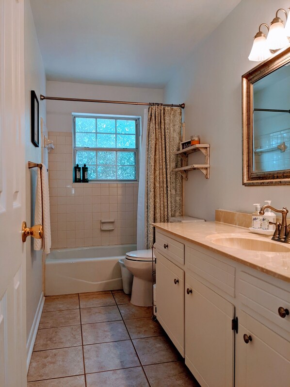 A bathroom with a bathtub, toilet, vanity with a mirror, and a window with frosted glass. - Little Getaway Paradise on the Golf Course w/Resort Amenities! (Holly Lake Ranch)