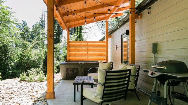 Un patio al aire libre con una parrilla, asientos y un jacuzzi.