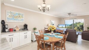 A dining area with a round table, chairs, and a chandelier. There is a map on the wall and a view of the outdoors through a sliding door. - Madeira Norte - The Perfect Beachfront Escape (Madeira Beach)