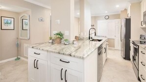 A modern kitchen with white cabinets, a marble countertop, and stainless steel appliances. - Madeira Norte - The Perfect Beachfront Escape (Madeira Beach)