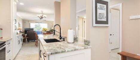 Una cocina moderna con armarios blancos, encimera de mármol y un lavabo empotrado.