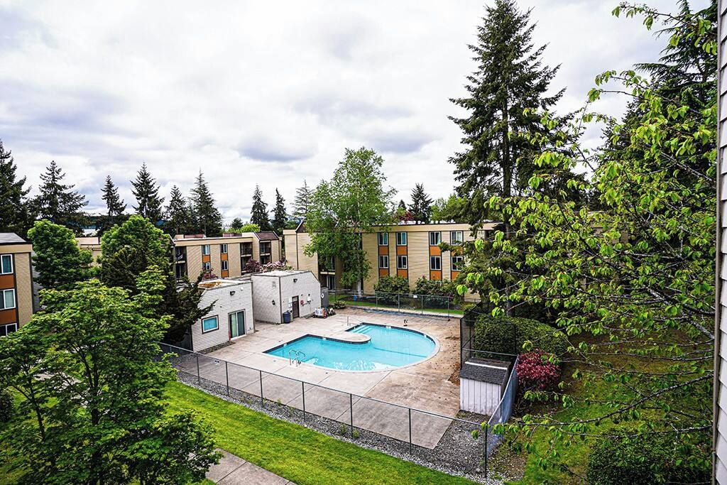A residential building with a swimming pool surrounded by greenery and trees.