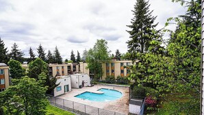 Edificio residencial con piscina rodeada de vegetación y árboles.