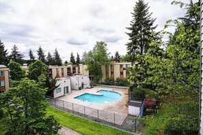 A residential building with a swimming pool surrounded by greenery and trees. - Modern Microsoft Redmond Campus Condo with Balcony (Bellevue)