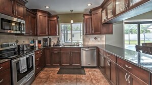 Una cocina con armarios de madera oscura, electrodomésticos de acero inoxidable y un amplio ventanal que proporciona luz natural.